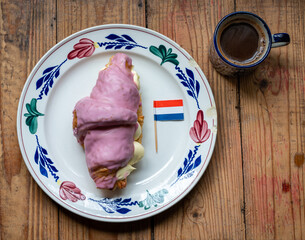A crompouce with dutch flag and a coffee.  A cross between a tompouce and a croissant that...