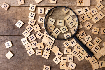 Magnifying glass with many wood letters of English alphabets, learning English concept - obrazy, fototapety, plakaty