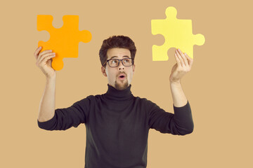 Young business man in a black turtleneck and geek glasses standing isolated on a beige background,...