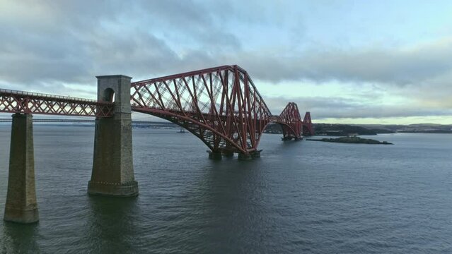Cinematic upwards reveal mid perspective aerial drone shot of Forth Rail Bridge, Scotland, Forth Road bridges come into view, clear winter day. 
