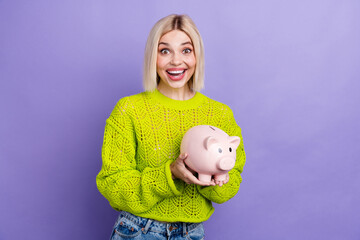 Photo of adorable excited lady wear green pullover collecting cash piggy money box isolated purple...