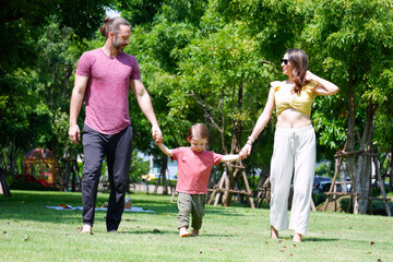 Happy father, mother and baby walking in the park.