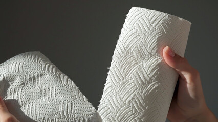 Female hands tear off piece of white paper towel from a roll