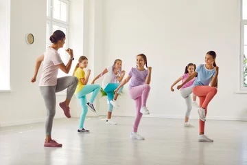 Crédence de cuisine en verre imprimé École de danse Children having a fitness workout with a trainer. Several kids doing sports exercises with a professional instructor. Group of girls in sportswear training together with a woman teacher at the gym