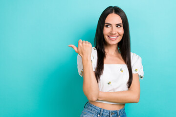 Photo of optimistic young woman look interested empty space point finger mockup billboard...