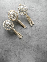 Transparent Christmas ball with weaving in macrame style, handmade decor in eco-style, top view on a gray background. Christmas, New Year and eco friendly concept.