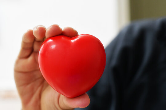 Persona con un coraz&oacute;n en la mano. Concepto de cuidado del coraz&oacute;n y la salud.