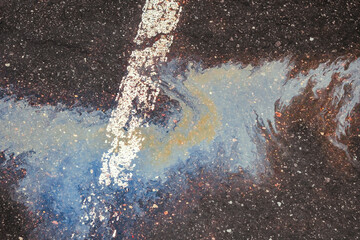 Oil spill on wet asphalt, parking lot with dividing line