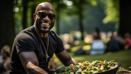 Keuken spatwand met foto Cheerful african american man eating salad in a park © Meow Creations
