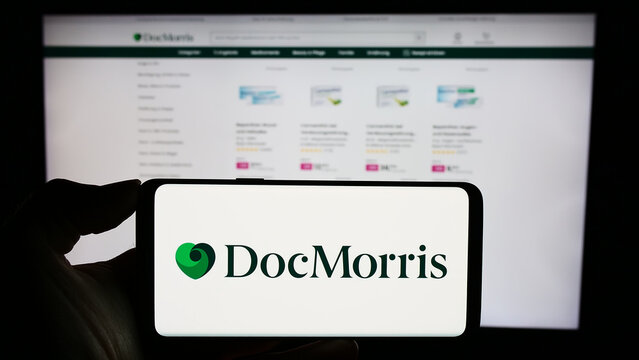 Stuttgart, Germany - 11-08-2023: Person holding cellphone with logo of Swiss online pharmacy company DocMorris AG in front of business webpage. Focus on phone display.