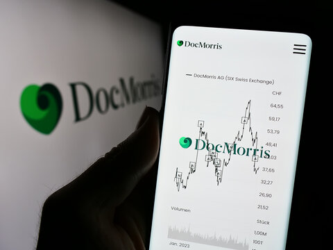 Stuttgart, Germany - 11-08-2023: Person holding cellphone with webpage of Swiss online pharmacy company DocMorris AG in front of logo. Focus on center of phone display.