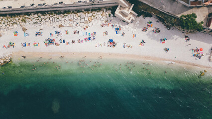 Top view, splendid aerial view of some people relaxing on a beautiful beach washed by the sea....