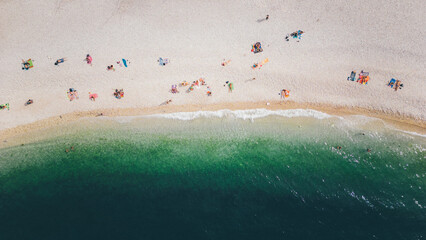 Top view, splendid aerial view of some people relaxing on a beautiful beach washed by the sea....