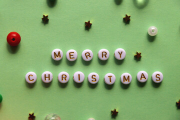 Various beads with Merry Christmas caption on green background. Top view.