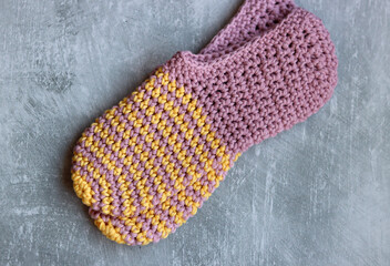 Handcrafted slippers made of organic yarn. Cute handmade footwear. Gray background with space for text. 