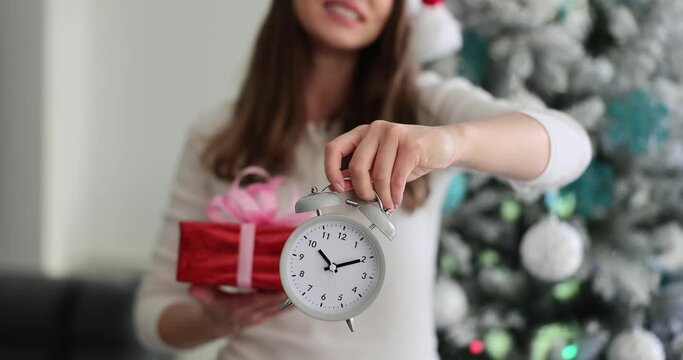 Woman hand holds gift box and an alarm clock