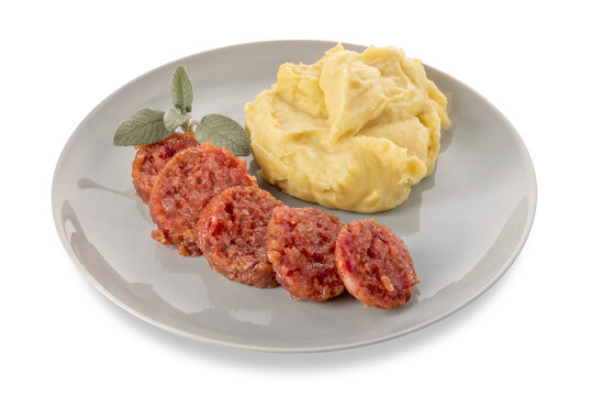 Slices of cooked sausage cotechino with mashed potatoes and sage leaves on plate isolated