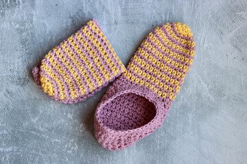 Handcrafted slippers made of organic yarn. Cute handmade footwear. Gray background with space for text. 