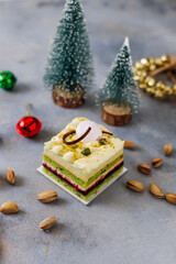 Fototapeta premium Pistachio cake slice with christmas decoration background.
