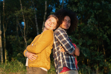 couple of friends, arabic guy and caucasian androgenic looking girl dressed as a boy, lesbian, enjoying golden hour together, sunset in the forest, tolerance concept, high quality photo