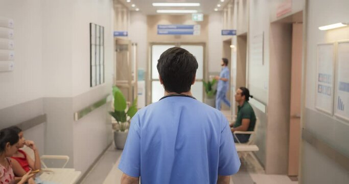 Backview Tracking Shot of Young Male Doctor Walking in Hospital Corridor. Slow Motion of Indian Professional Medical Specialist Starting his Workday in a Busy Modern Health Clinic