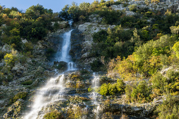 The Spissula waterfall. Beautiful Italian cascade on the Julian alps during a sunny fall day. Scenic nature spectacle. Trasaghis, Udine province, Friuli Venezia Giulia, Italy.