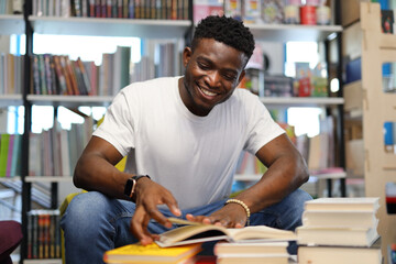 Focused African American student in a university library, immersed in studying amid bookshelves,...
