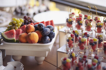 fruits and berries in glass. Catering on wedding. Wedding banquet table. Sweet table with fruits. Fruit bar on party. Delicious fruits appetizers, desserts on stand, modern tab. Fruit bar on party