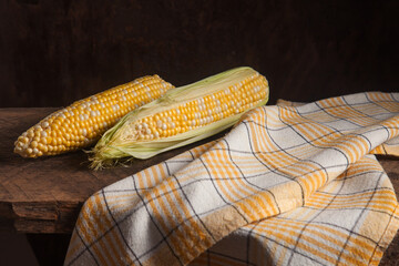 Two cobs sweet corn on wooden background..
