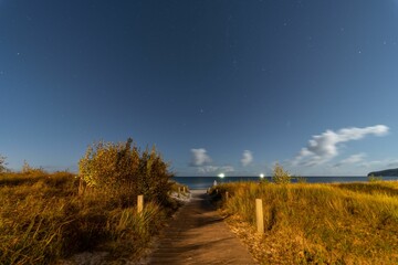 Long exposure shot of a starry night sky over a beach path in the Baltic Sea.