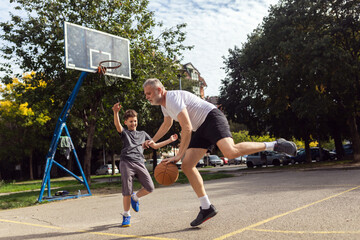 Mature man playing basketball with his son