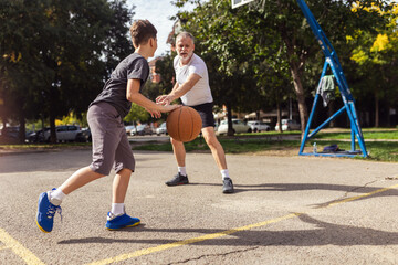 Mature man playing basketball with his son