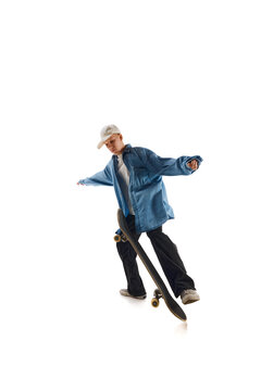 Dynamic image of teen boy in blue shirt and capo training, in motion, skateboarding isolated over white background. Concept of professional sport, competition, training, action. Copy space for ad