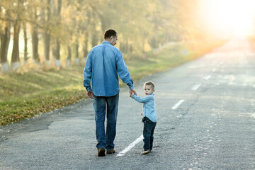 A Happy parent with child are walking along the road in the park on nature travel