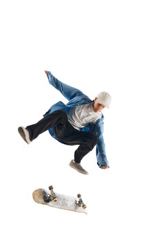 Dynamic image of sportive young man in casual clothes in motion, raining, jumping with skateboard isolated over white background. Concept of professional sport, competition, training, action.