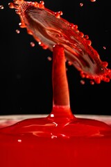 Vertical closeup of red paint drop collision