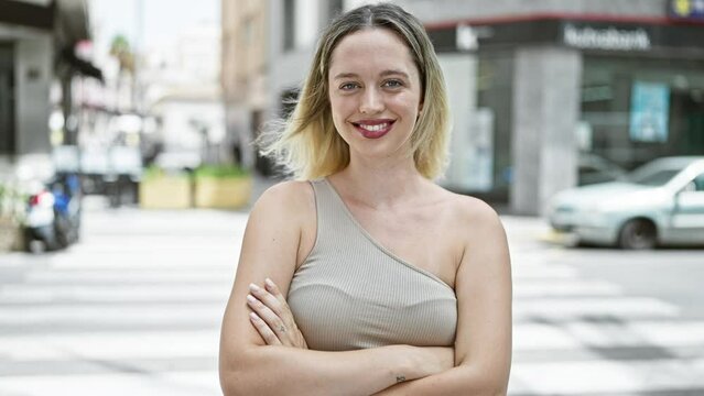 Young blonde woman smiling confident standing with arms crossed gesture at street