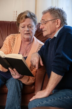 Help the Aged: Bible Reading. A senior couple referring to their Bible. From a series of related images.