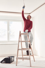 Handyman electrician with ladders working in a new home interior.