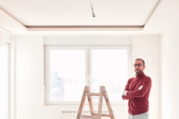 Handyman electrician with ladders working in a new home interior.