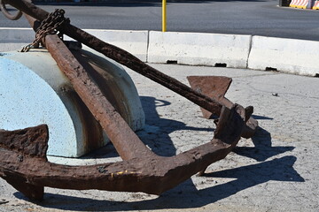Close view on two old rusty anchors with chain placed in the middle of roundabout with traffic sign...