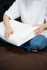 Orthopedic pillow for sleeping, a girl strokes a white foam pillow with her hand.