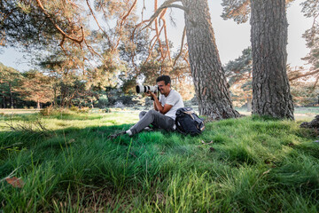 Young latin man is exploring in the forest with his binoculars.