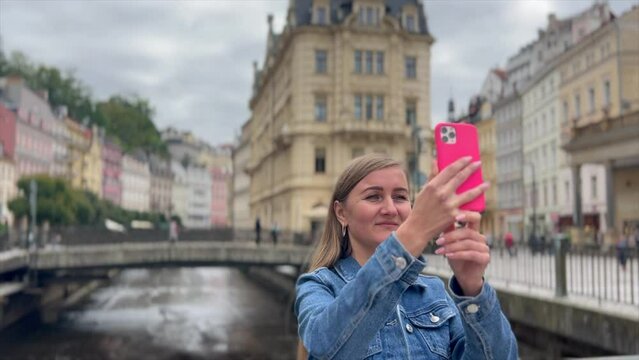 A woman tourist takes photos of a beautiful European city on her smartphone
