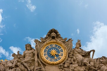 Versailles, France. Large blue clock with golden details, the Sun and the Fleur de Lis, statues and...