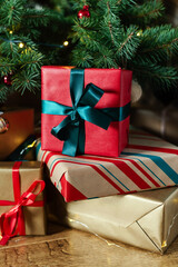 Stack of gifts in the lights of a garland under the Christmas tree.