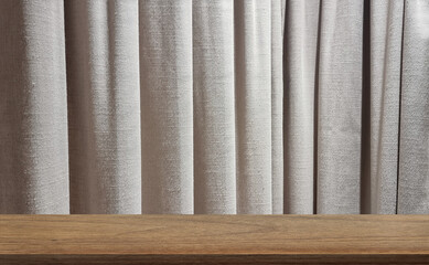 beige sackcloth curtains at background with oak wooden table at foreground. image monatge for product displayed in minimal mood and tone. empty wood table with grey draped.