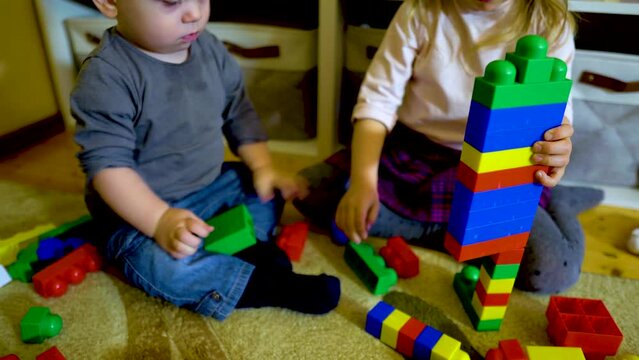 Caucasian girl and boy playing at home. Child playing with colored constructor on floor. Educational and creative toys. Development of fine motor skills. Happy family preschool education Kindergarten