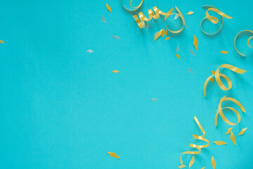 close up on group of gold color of rolling ribbon and confetti on teal background with copy space...