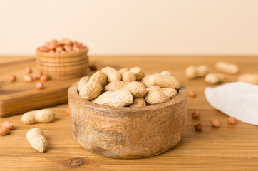Peeled and unpeeled peanuts on wooden table
